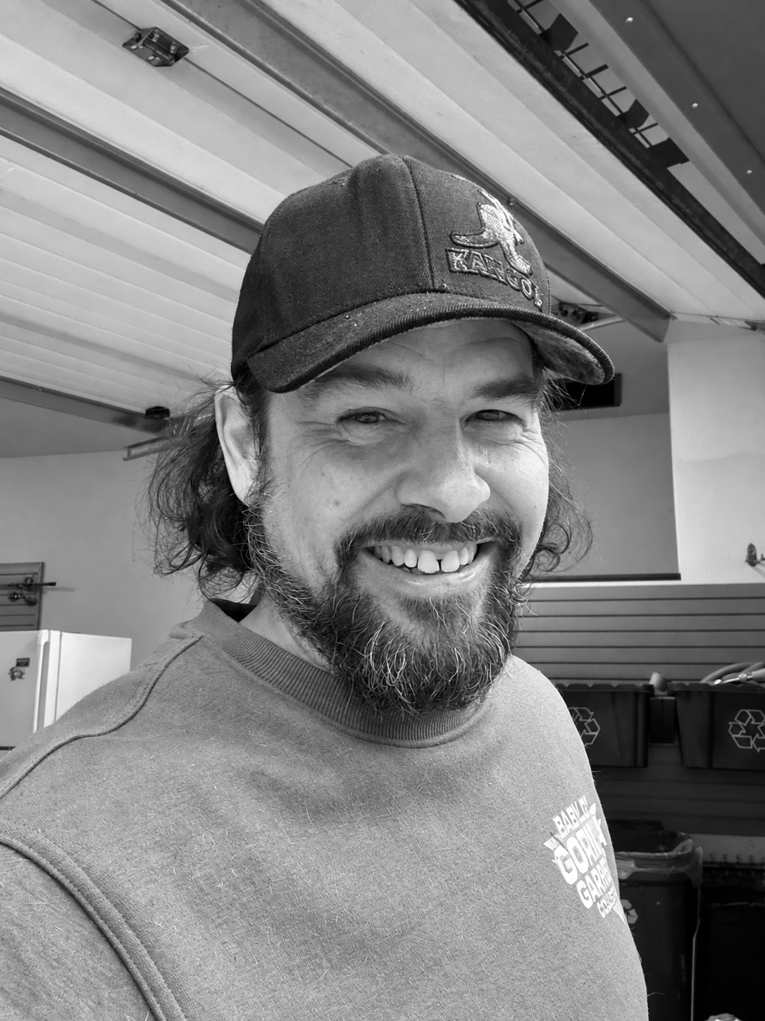 Keith smiling in a cap, in the supplied photograph converted to black and white.